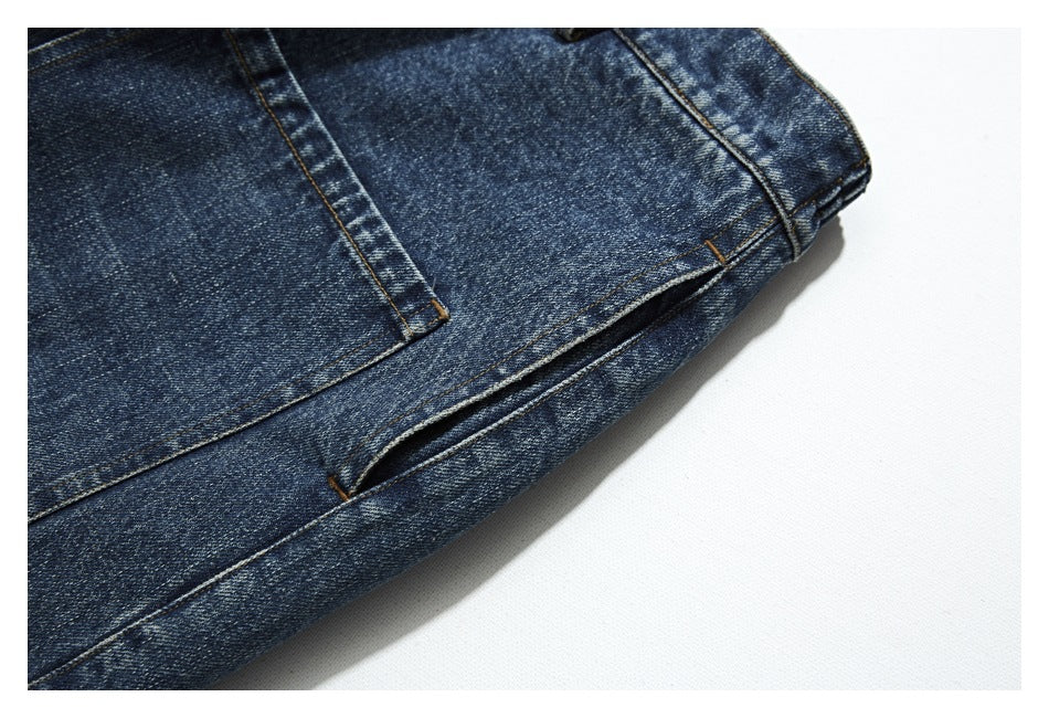 Close-up of dark blue washed denim trousers showing a rear pocket, seam, and hem.