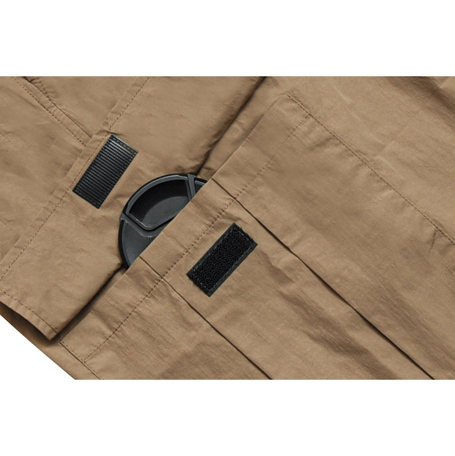 Close-up of tan trousers showing stitched panels and two black hook-and-loop tabs.