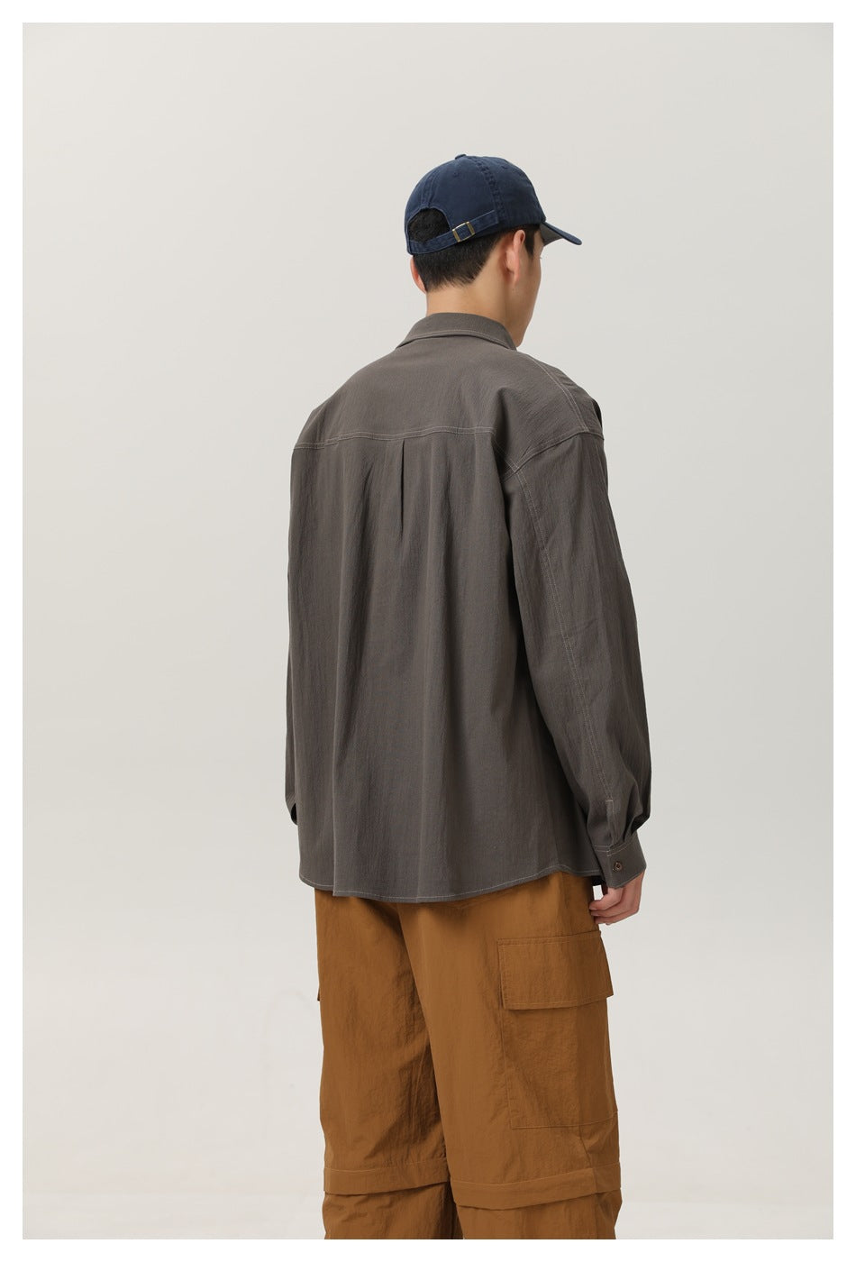 Rear view of a man in a charcoal gray shirt and brown cargo pants, showing the shirt's back and shoulder seams.