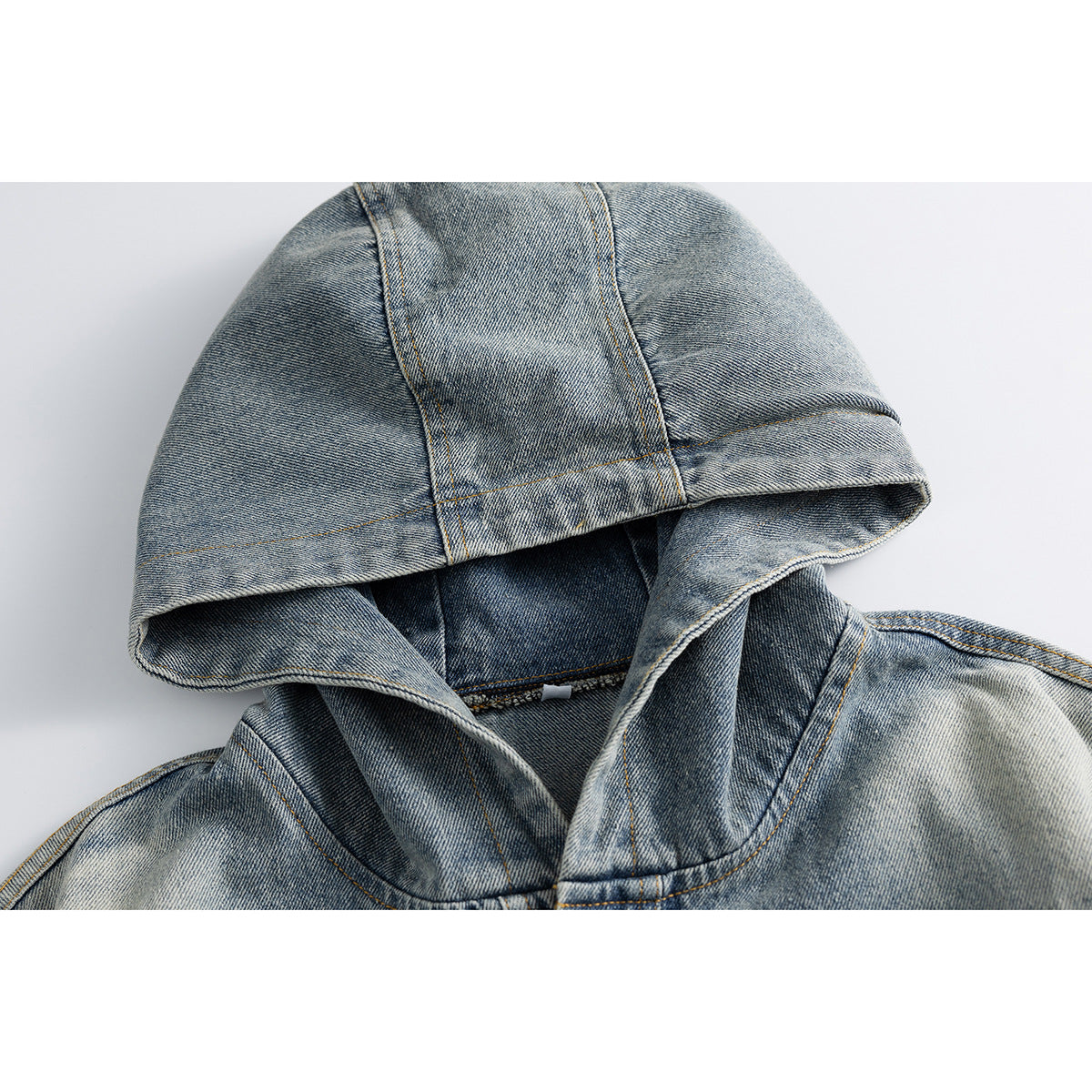 Close-up of a faded blue denim jacket's hood and collar with contrast stitching.