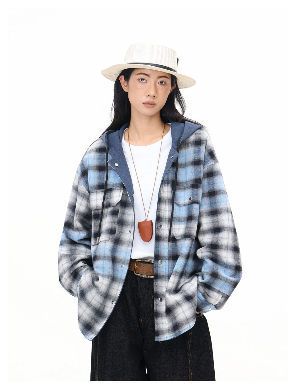 Close-up of a model wearing the open blue plaid hooded jacket over a white tee with a straw hat, necklace and belt