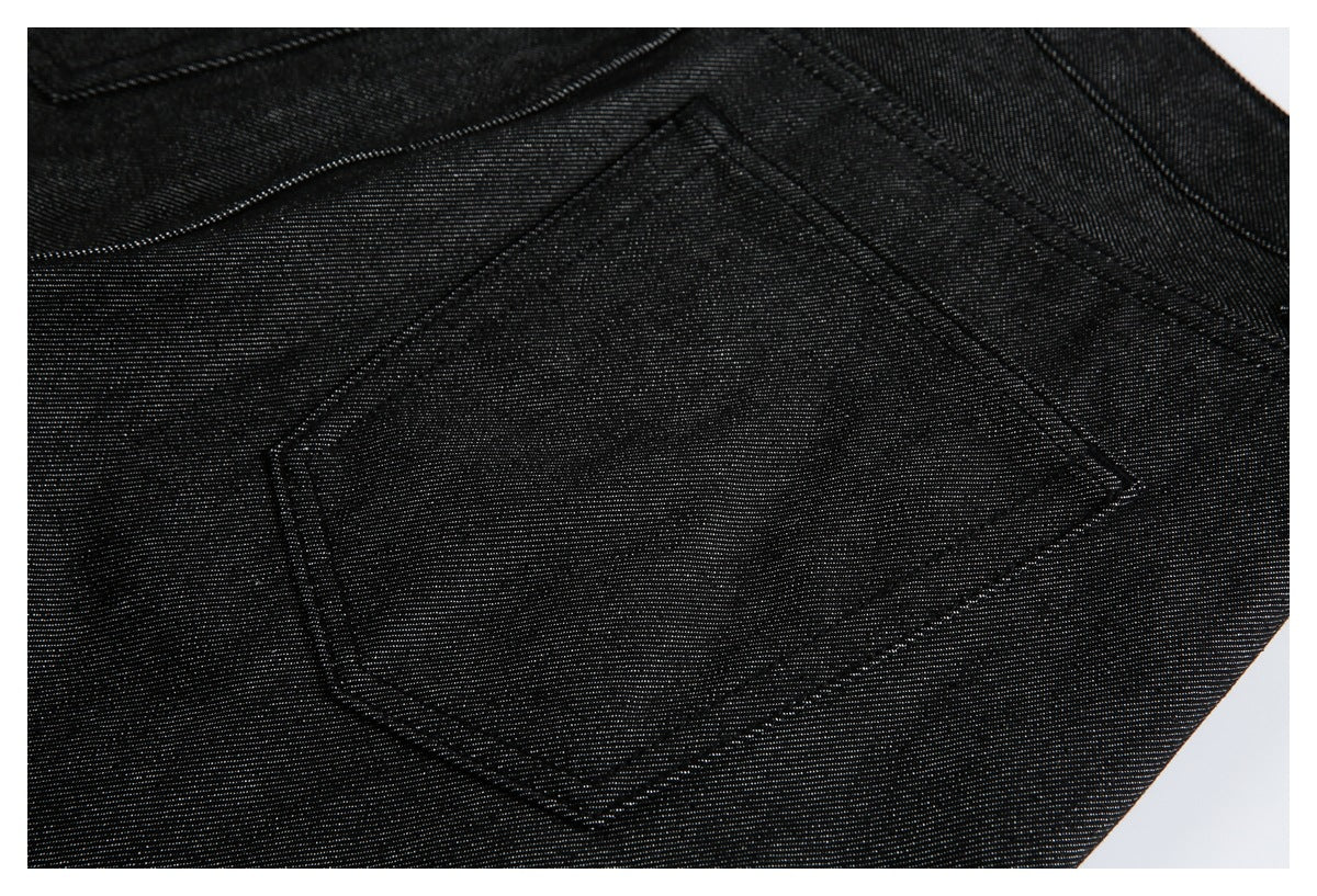 Close-up of a stitched patch pocket on black denim trousers.