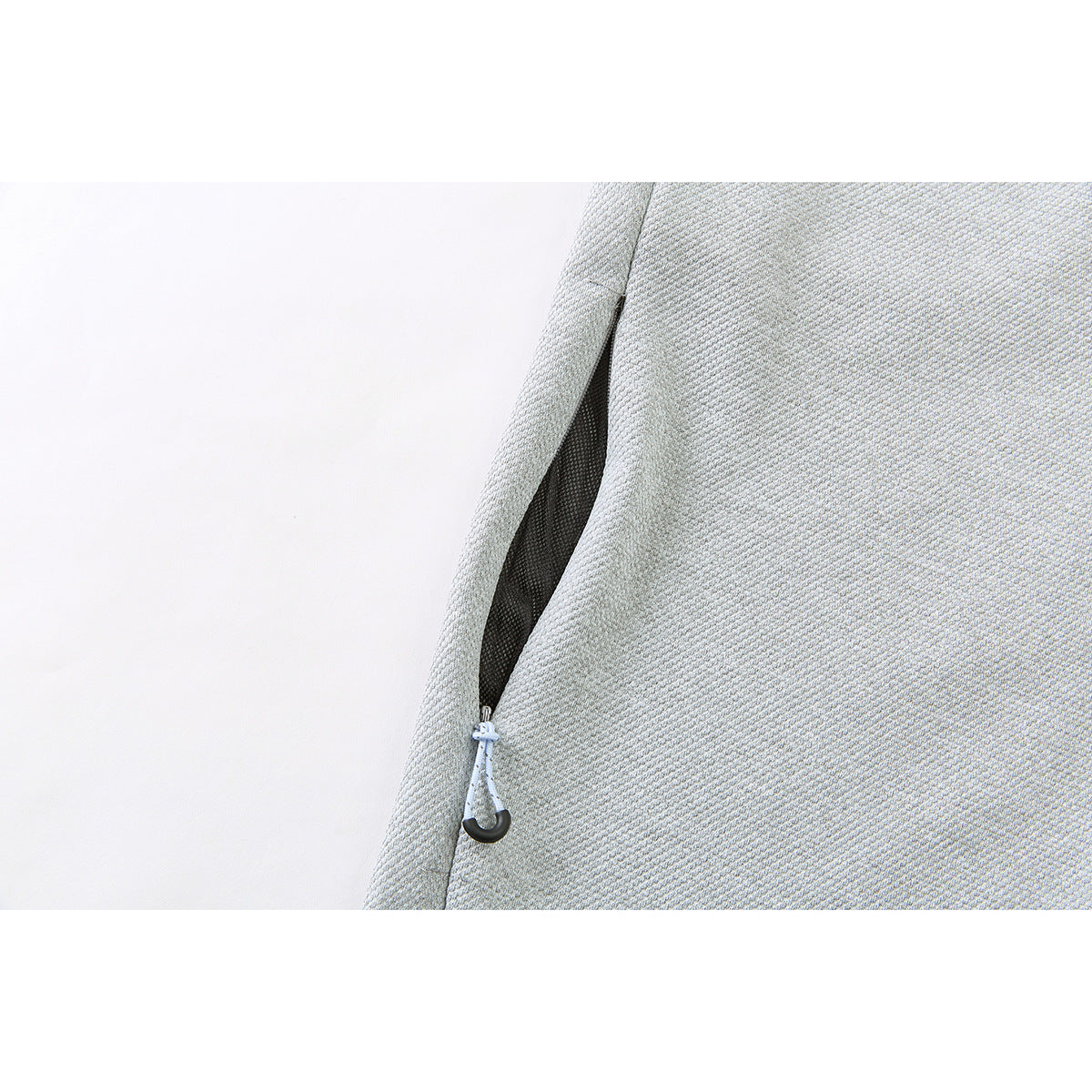 Close-up of a black zippered pocket with a light-colored pull on light gray pants.