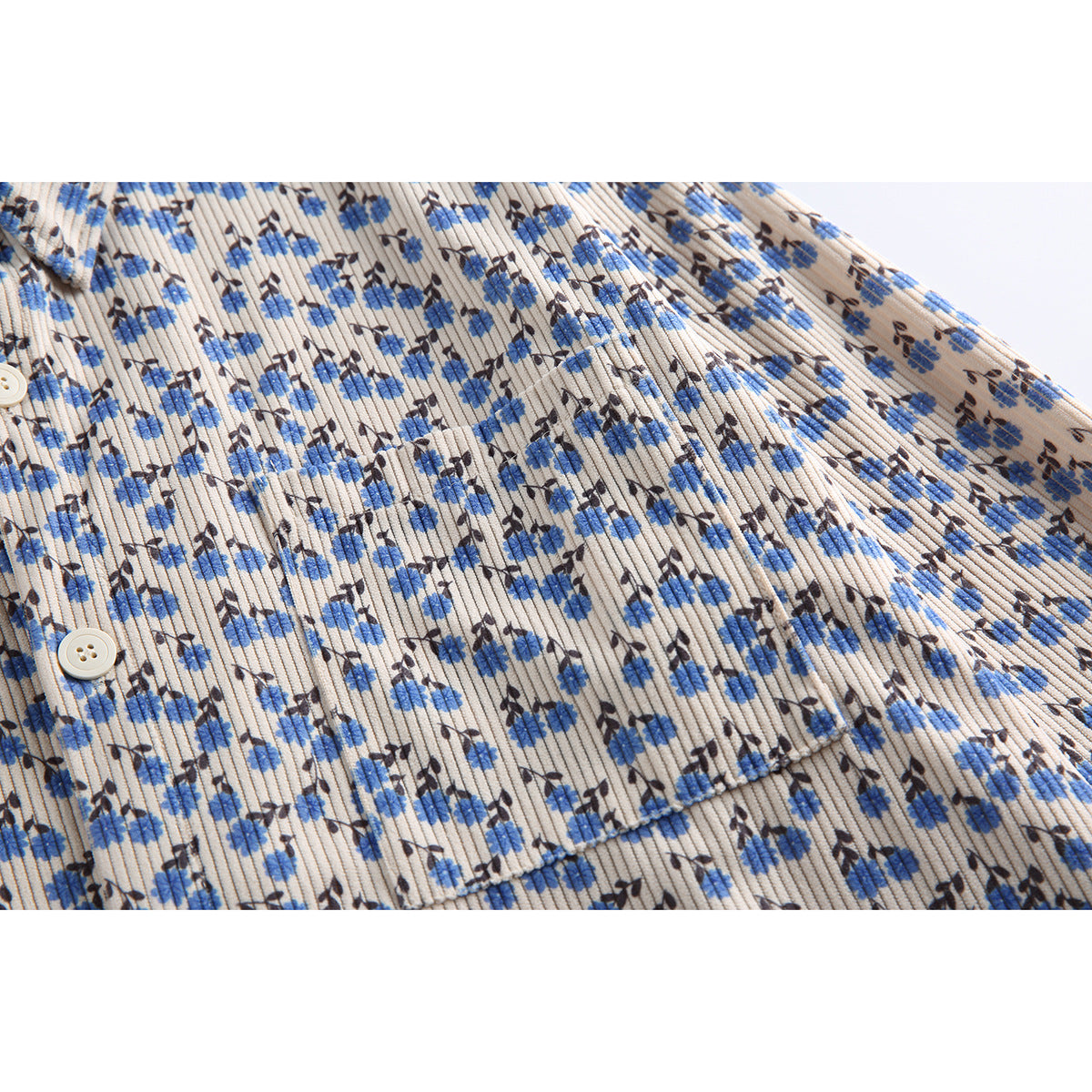 Close-up of a beige ribbed shirt with blue and dark floral print, showing a button and chest pocket.