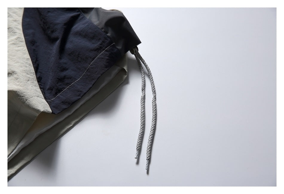 Close-up of a navy jacket sleeve with two patterned adjustment cords hanging from its cuff.