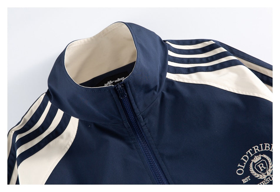 Close-up of the navy jacket's stand collar, front zipper, cream shoulder panels, and sleeve stripes.