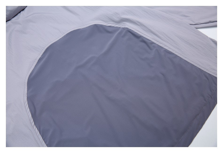 Close-up of a large dark gray curved inset panel on a light gray pinstriped garment.