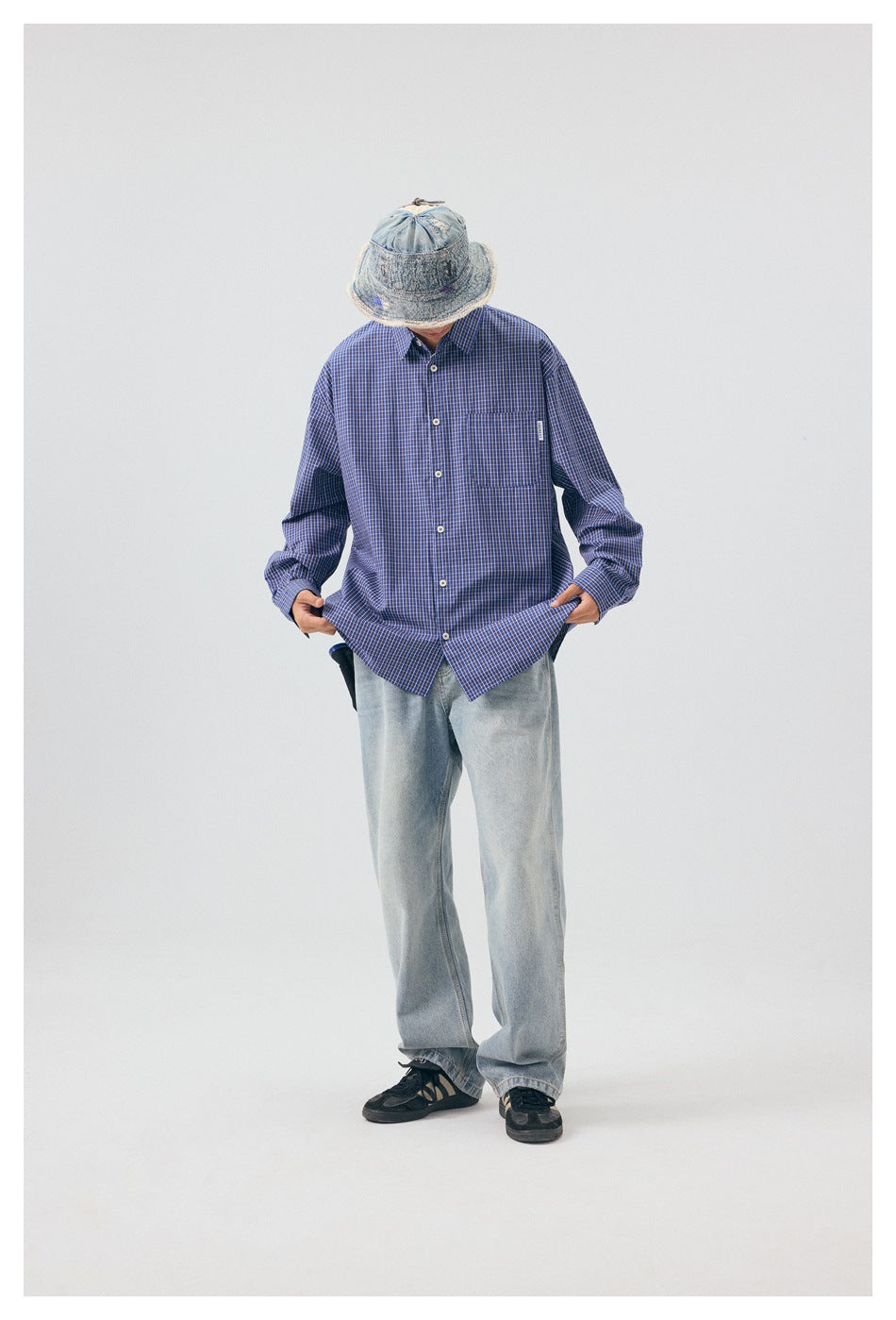 Full-length model wearing a blue checked button-up shirt with a chest pocket and loose light-wash jeans.