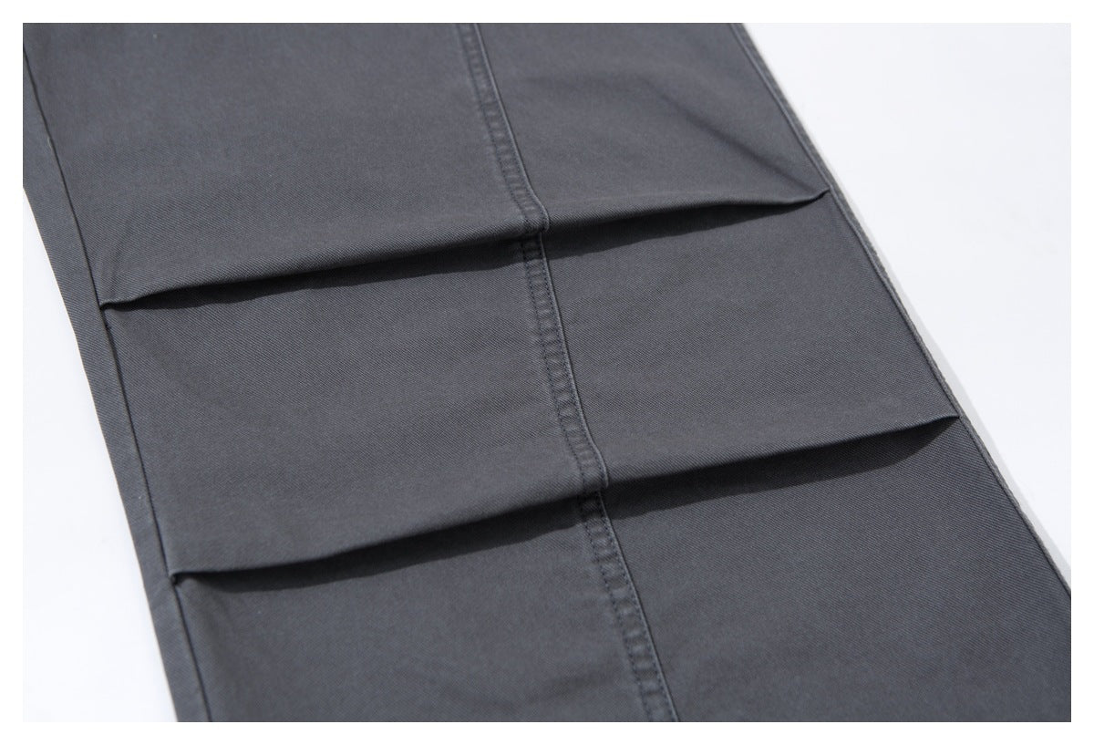 Close-up of charcoal trouser fabric with stitched vertical seams and folded horizontal panels.