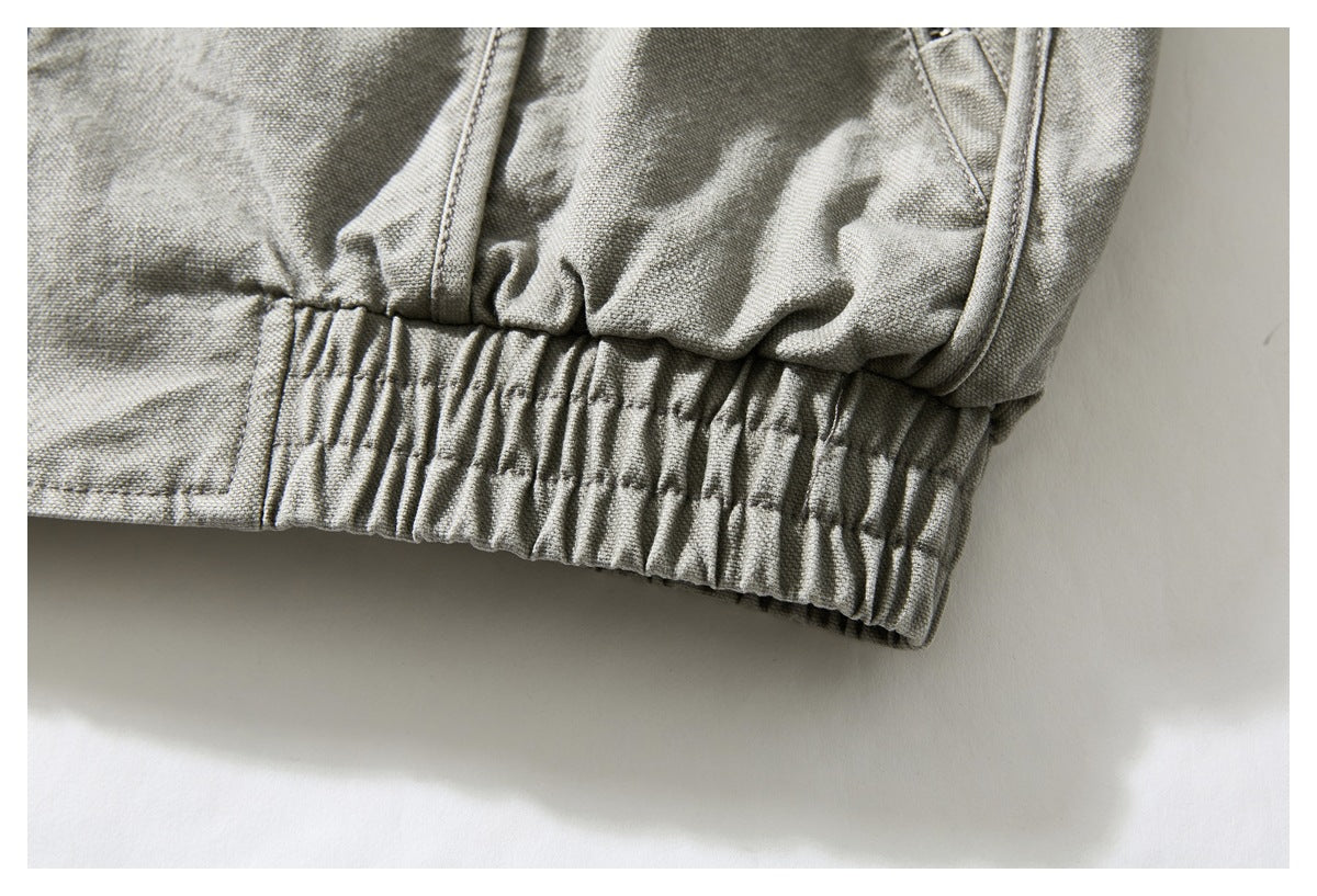 Close-up of a gray-green jacket's gathered elastic hem and stitched panels.
