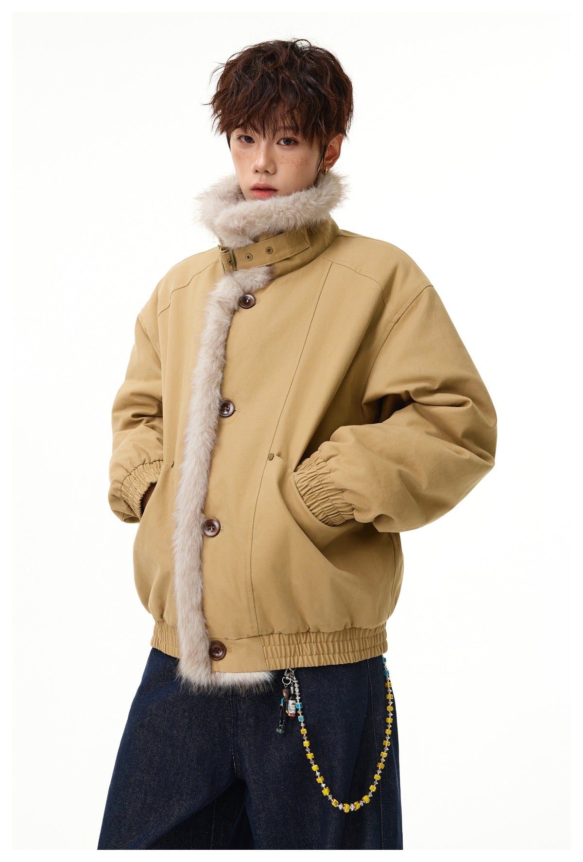 Model wearing a tan jacket with oversized pale faux-fur trim, brown buttons, gathered cuffs and hem, and dark jeans.