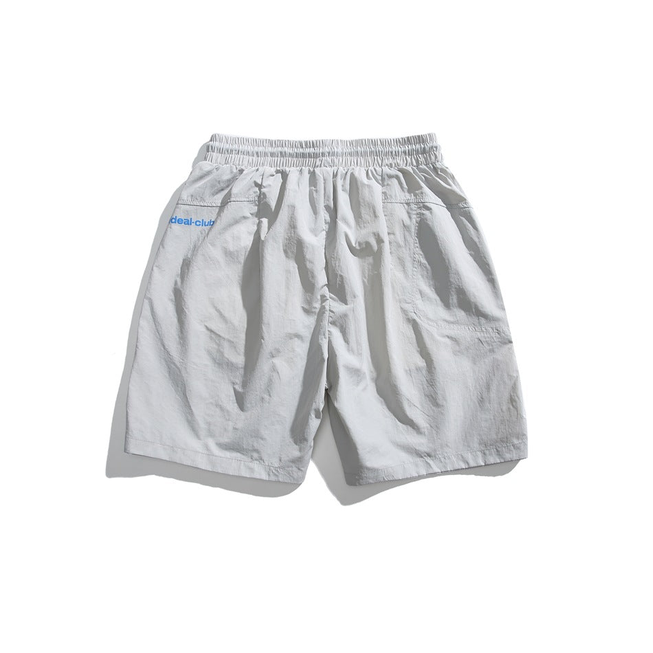 Back view of light gray shorts with an elastic waistband, rear pocket, and small blue logo.