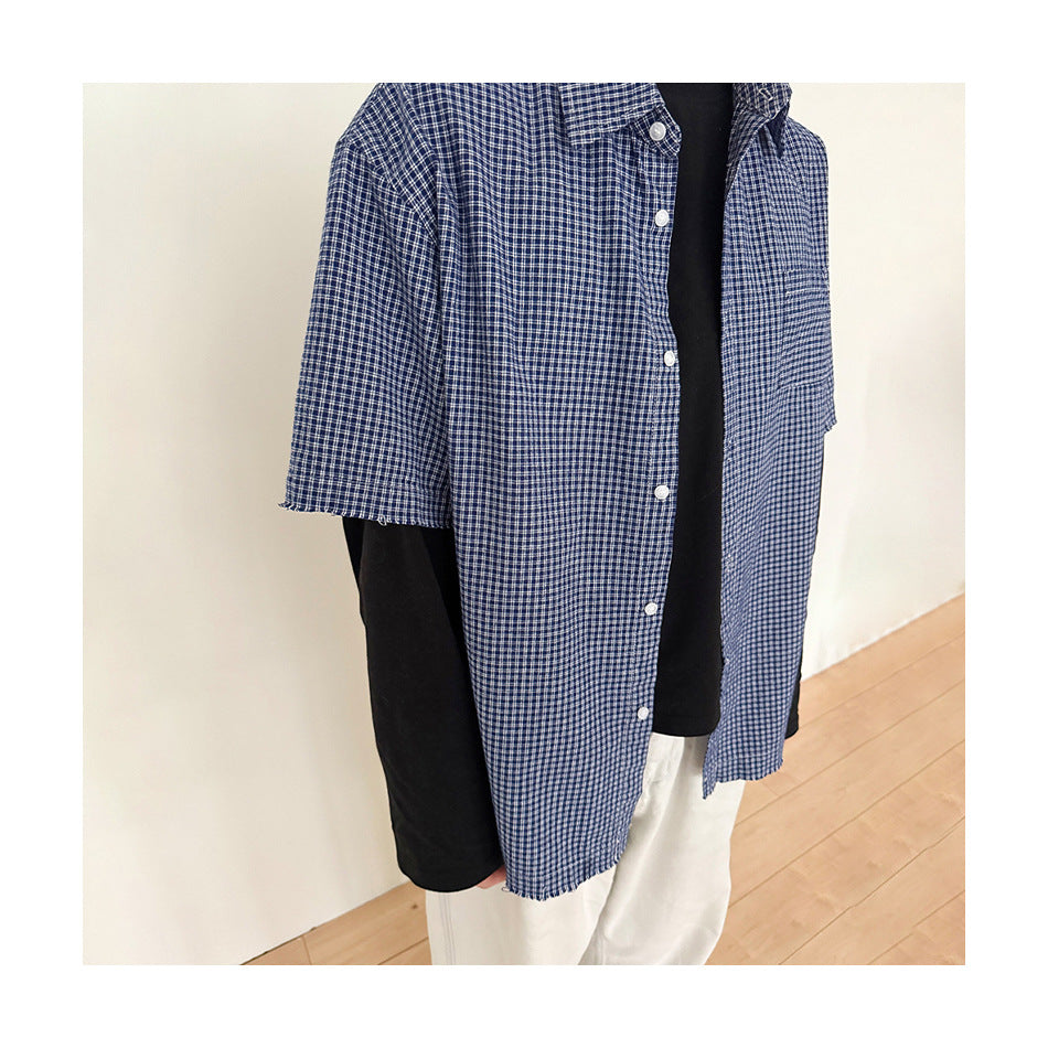 Person wearing an open blue gingham short-sleeve shirt over a black long-sleeve top and white pants, showing frayed hem