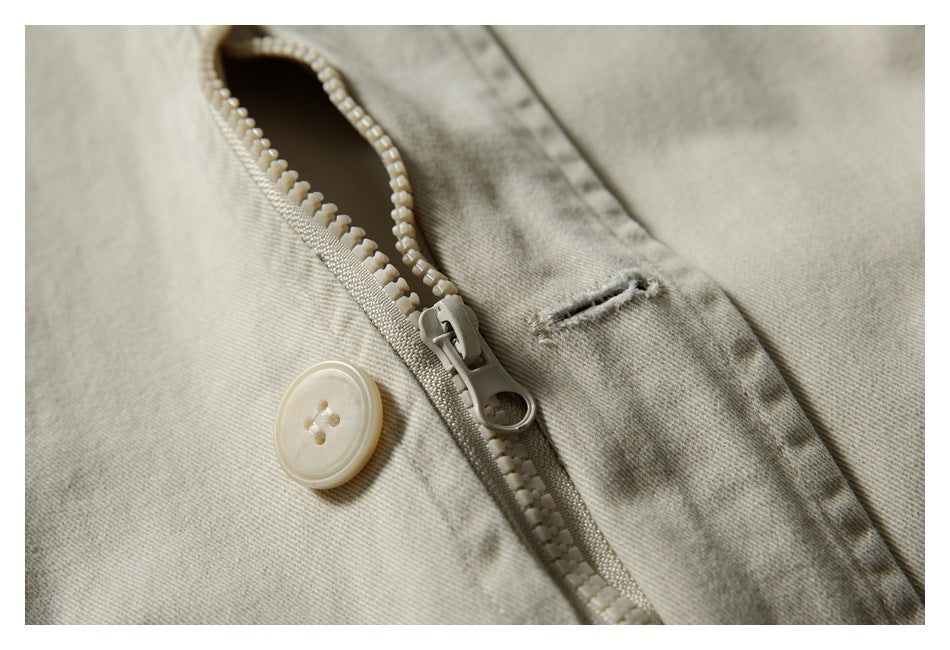 Close-up of a beige garment zipper, button, and stitched buttonhole.