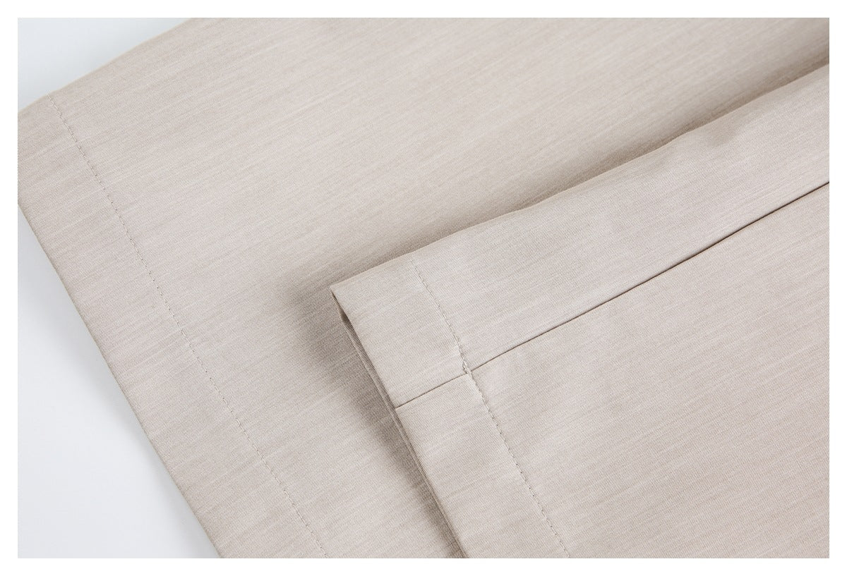 Close-up of beige trouser fabric showing a stitched edge and folded seam.