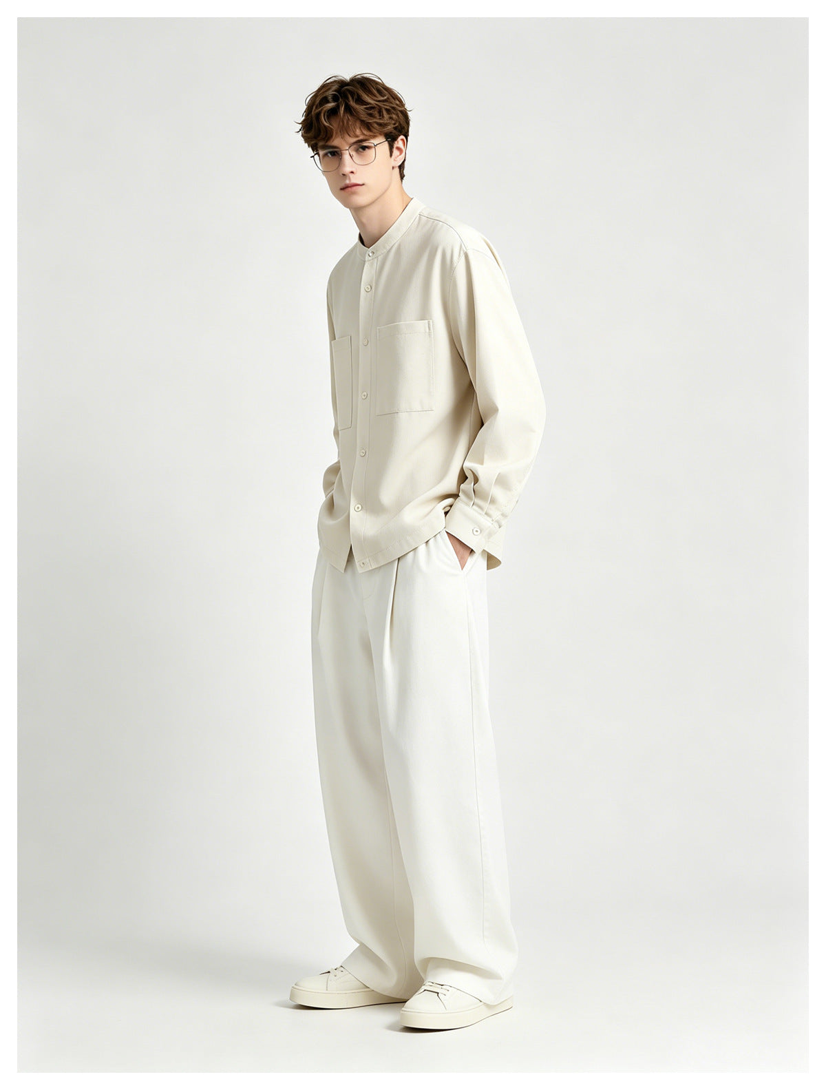 Model wearing the beige collarless button-front shirt jacket with wide white trousers and sneakers, front three-quarter view