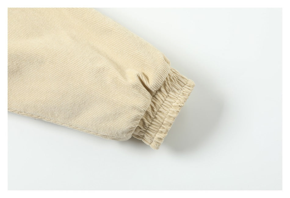 Close-up of a cream corduroy jacket sleeve ending in a gathered elastic cuff.