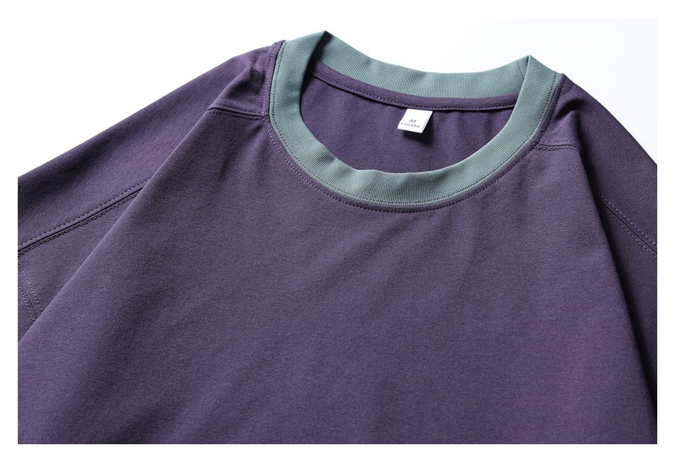Close-up of the purple sweatshirt's teal ribbed neckline, shoulder seams, and upper chest.