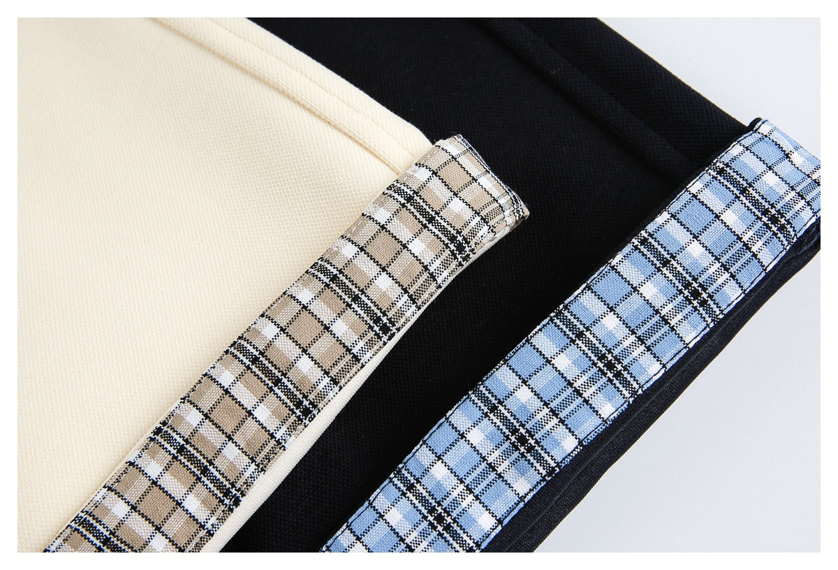 Close-up of tan and blue plaid trim along cream and black garment edges.