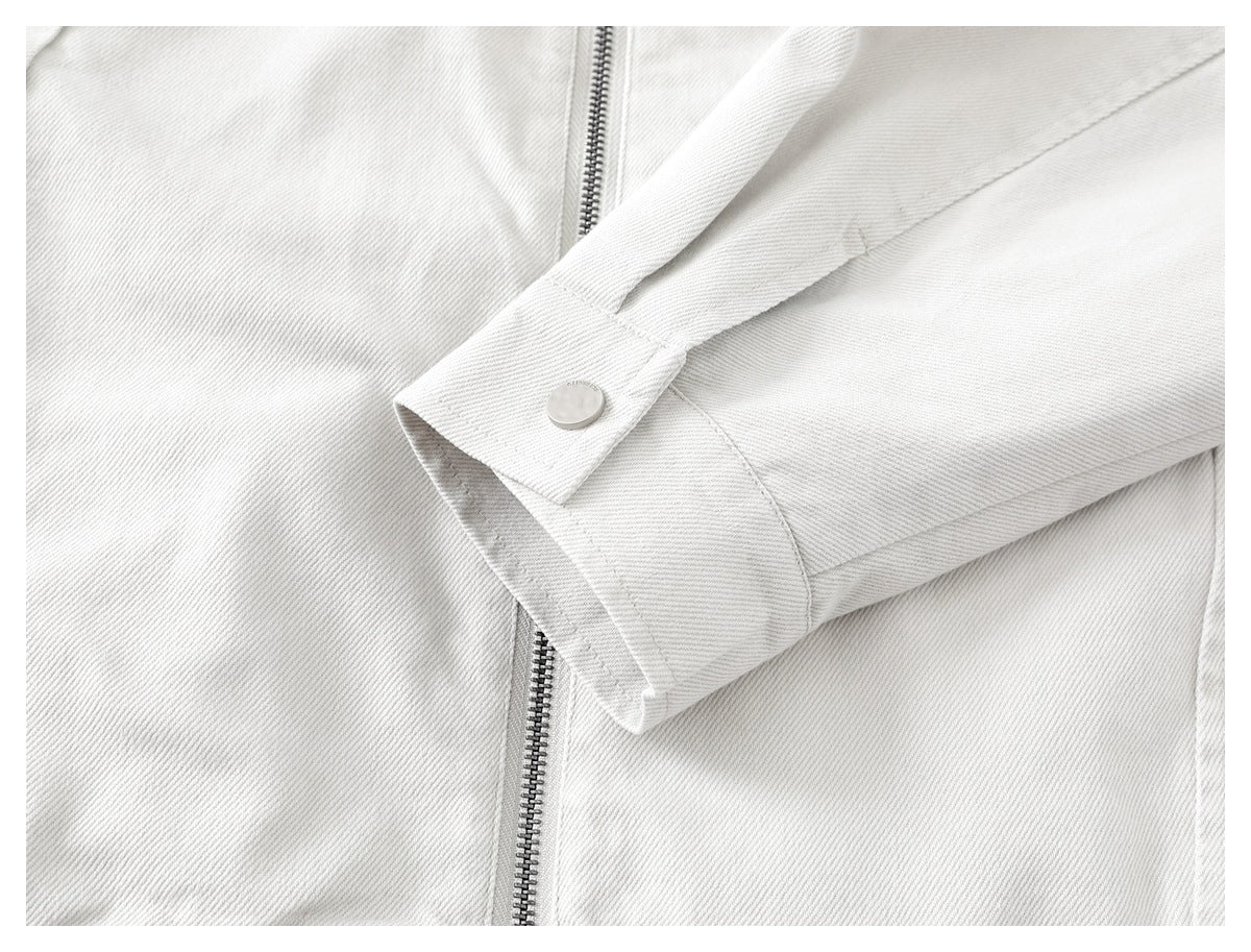 Close-up of an off-white jacket sleeve cuff with a round snap button beside the front zipper.