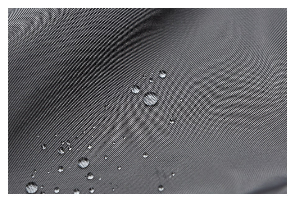 Water droplets bead on dark gray fabric, showing its textured surface.