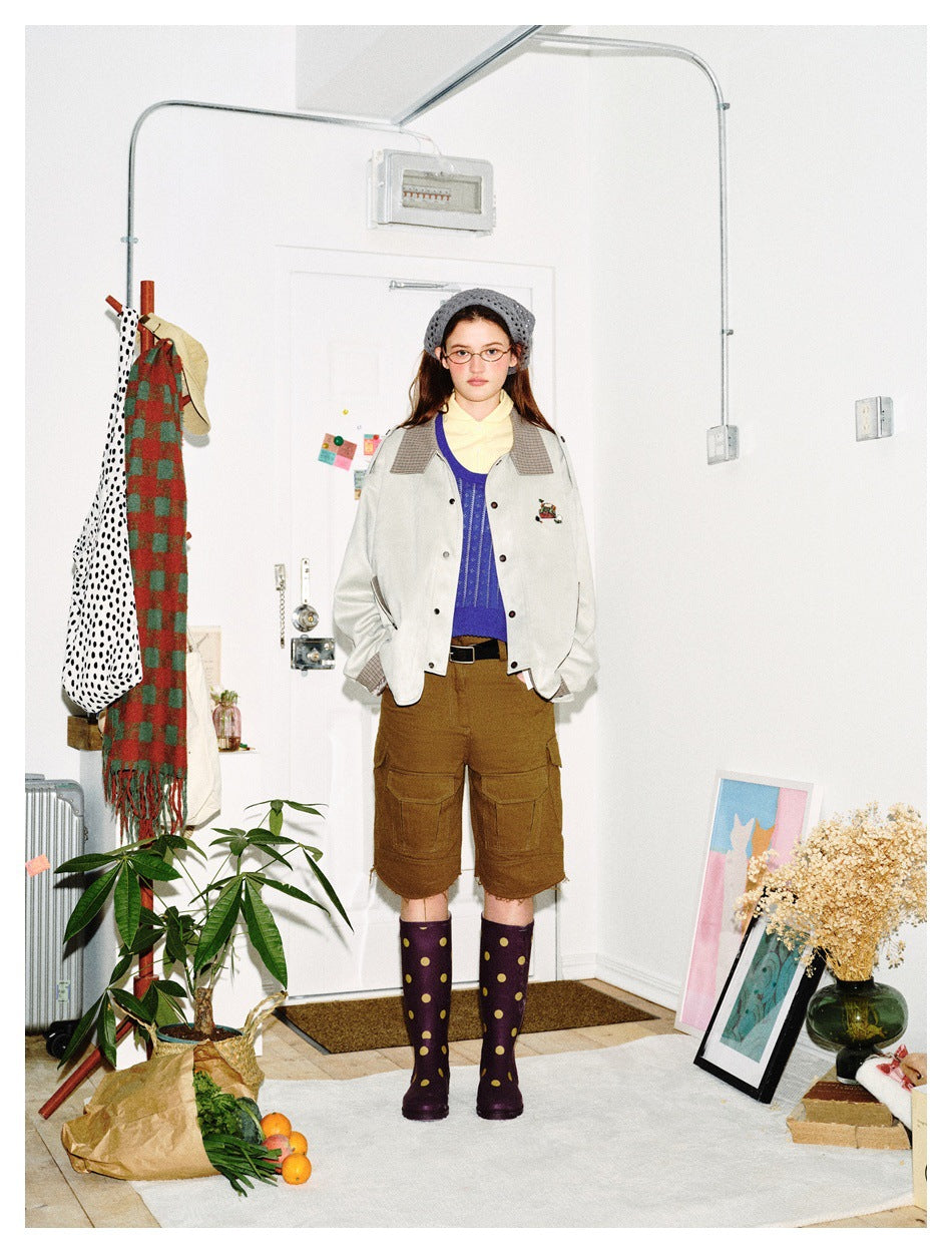 Full-length model wearing a pale gray checked-trim jacket, brown cargo shorts, and purple boots with yellow dots.