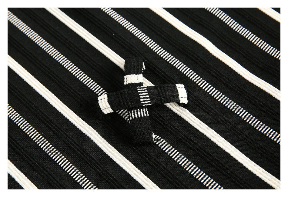 Close-up of black fabric with cream and narrow white striped lines and a small sewn fabric loop.