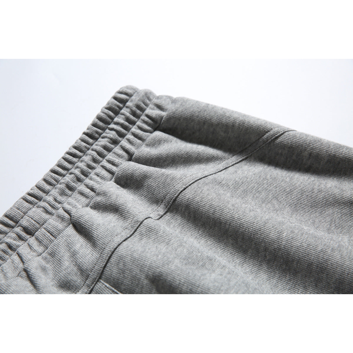 Close-up of heather gray sweatpants showing the gathered elastic waistband and back pocket seam.