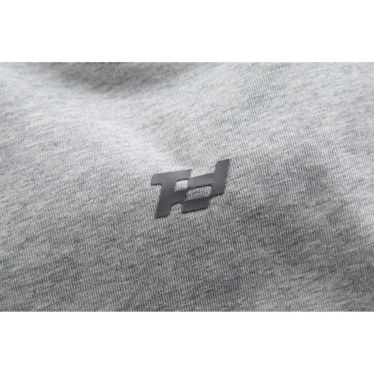 Close-up of a small dark emblem on heather gray knit fabric.
