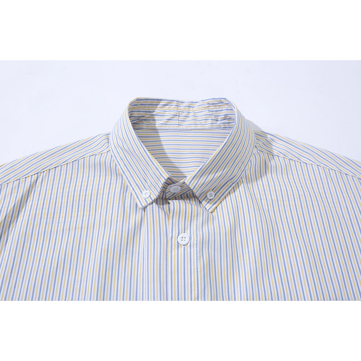 Close-up of a white button-down shirt collar and upper placket with fine blue and mustard vertical stripes.