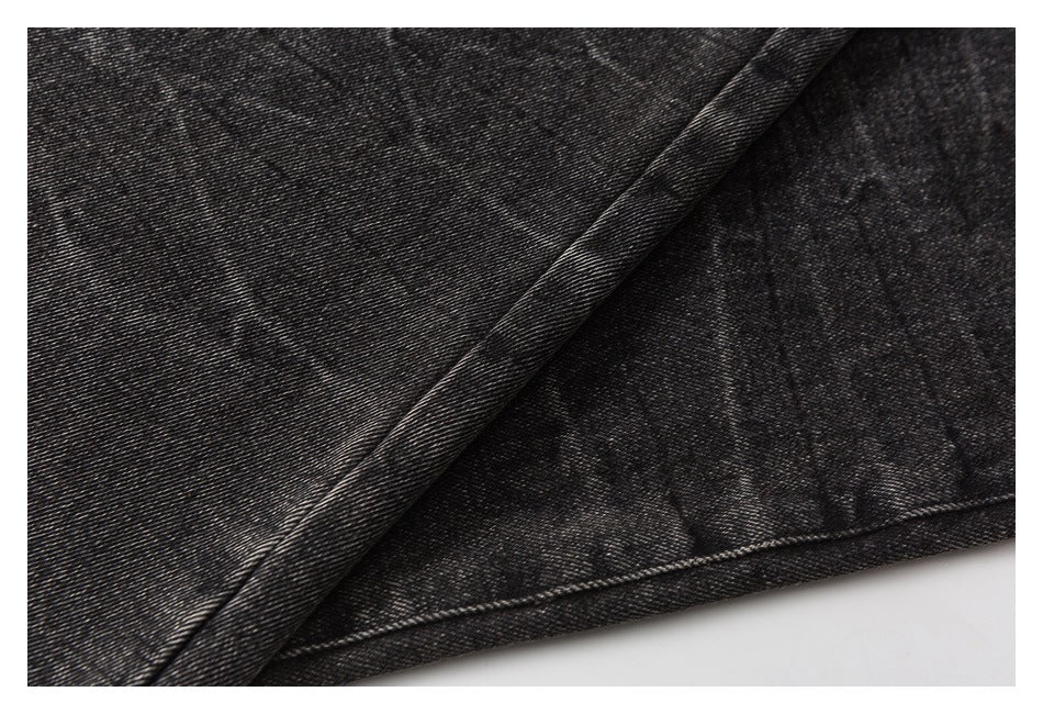 Close-up of charcoal washed denim folded to show its diagonal weave and stitched edge.
