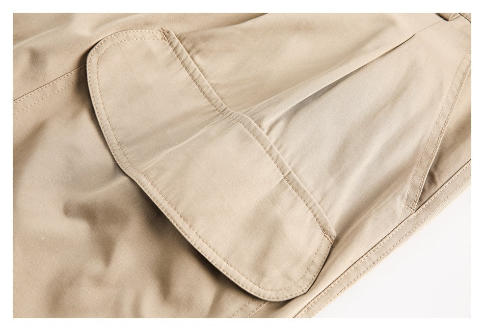Close-up of a beige trouser pocket flap with curved stitching and nearby seams.
