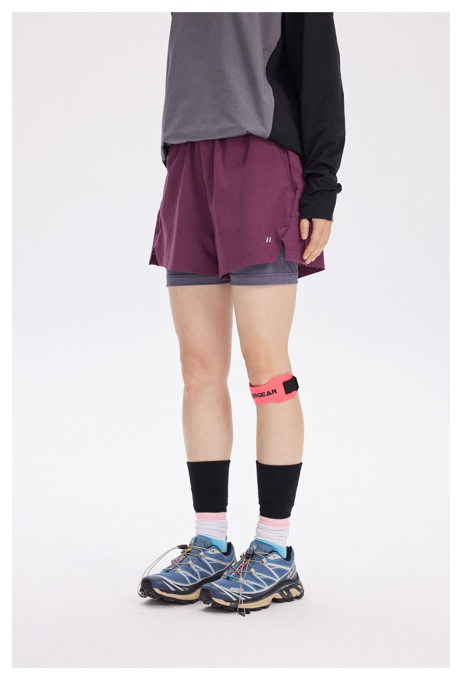 Front view of a model wearing burgundy running shorts over gray compression shorts.
