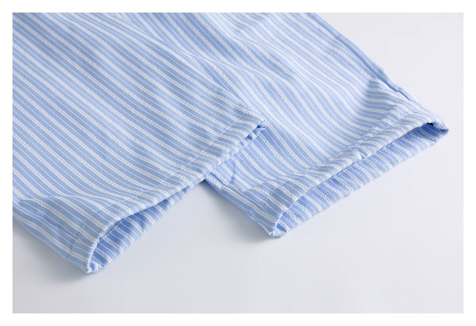 Close-up of the stitched hem on light blue shorts with narrow white stripes.