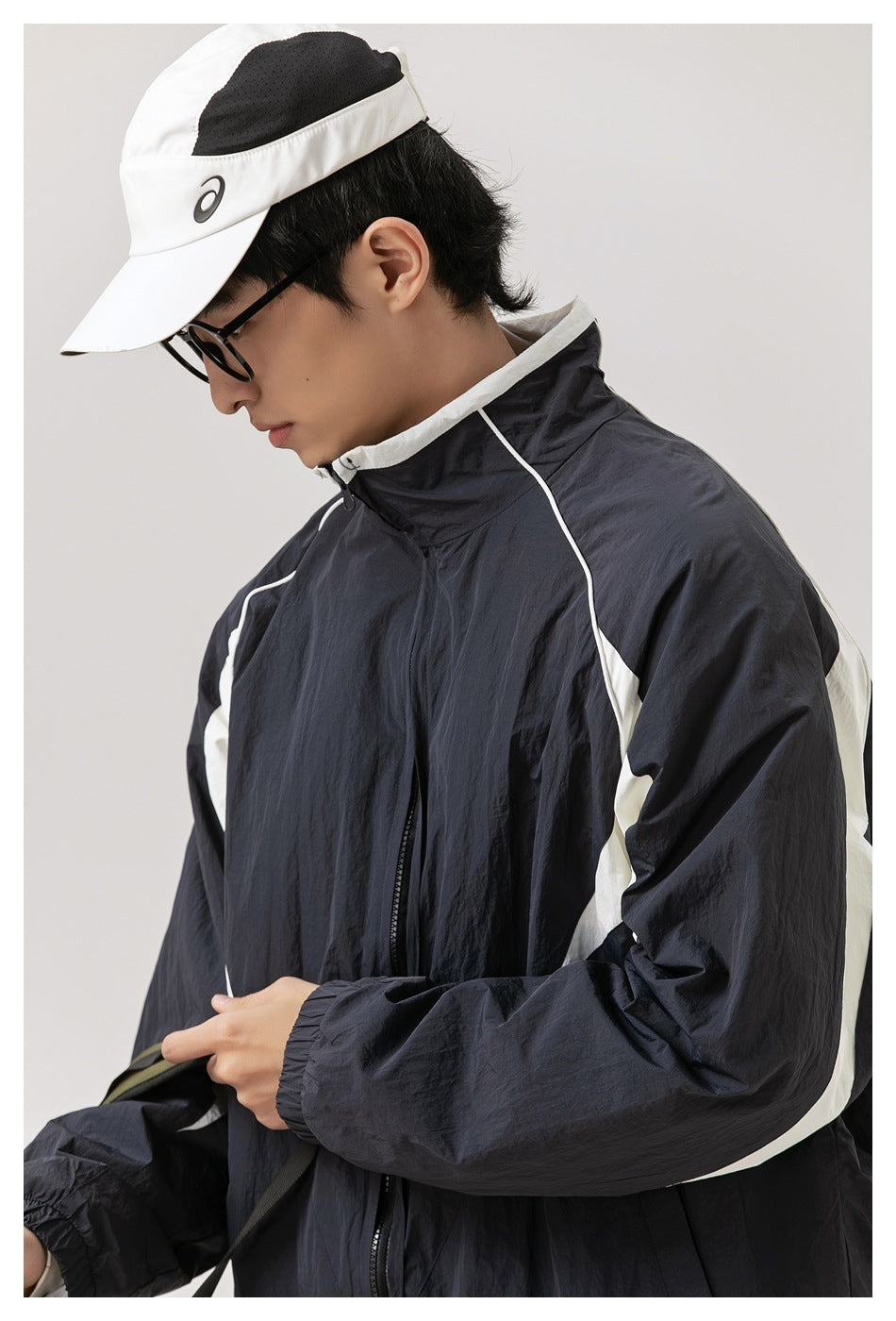 Close view of the jacket's high collar, front zipper, white piping, and white sleeve panels.