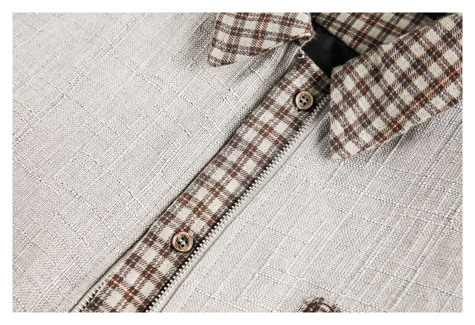 Close-up of the cream garment's brown plaid trim, zipper, buttons and collar.