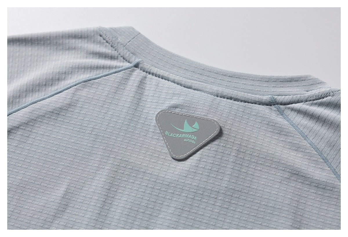 Close-up of a triangular BLACKARMADA outside patch on the back neckline of a light gray textured shirt.