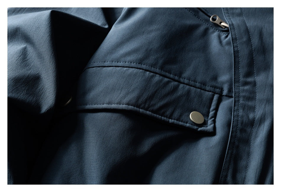 Close-up of a dark jacket flap pocket with a metal snap and nearby zipper.