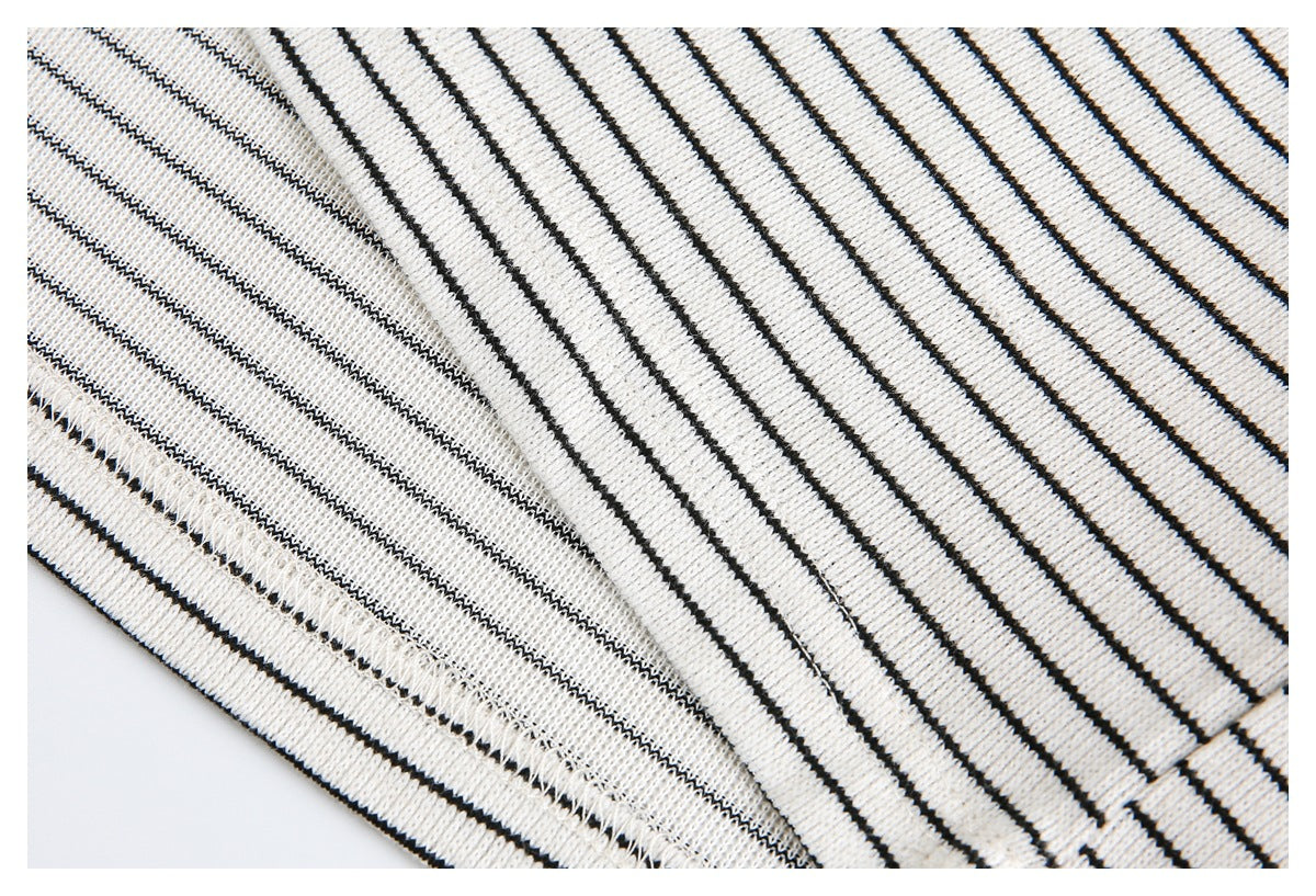 Close-up of a seam on cream knit fabric with thin black stripes, showing the reverse stitching.