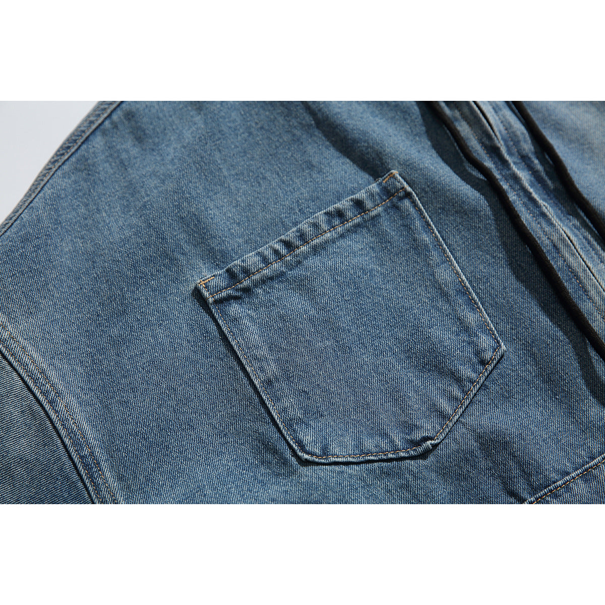 Close-up of a blue washed-denim jacket's stitched chest pocket and surrounding seams.