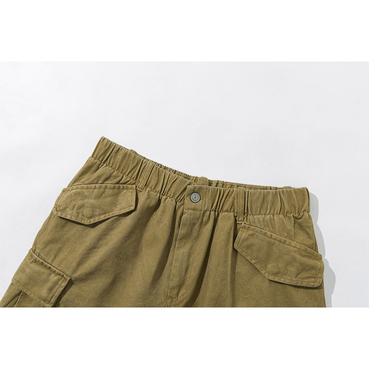 Close-up of olive cargo shorts showing the elastic waistband, button, and flap pockets.