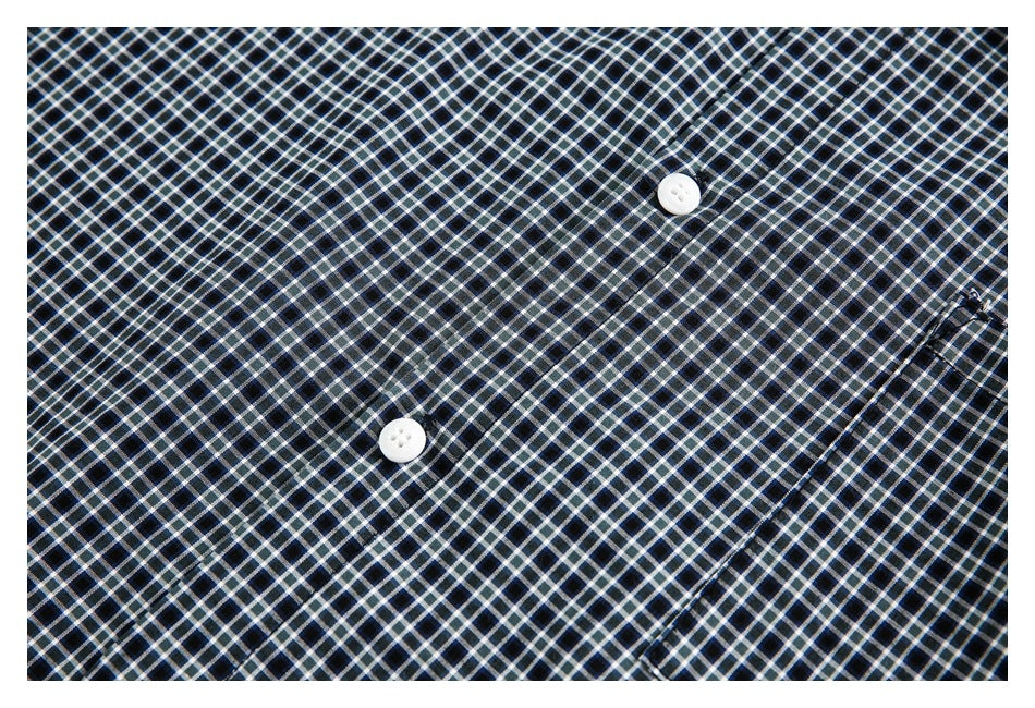 Close-up of black, white, and blue checked shirt fabric, with two white buttons and a seam.