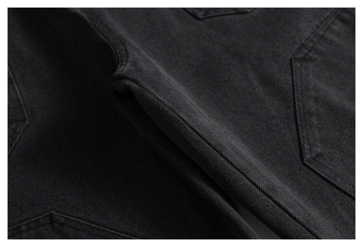 Close-up of black denim with diagonal seams and part of a pocket.