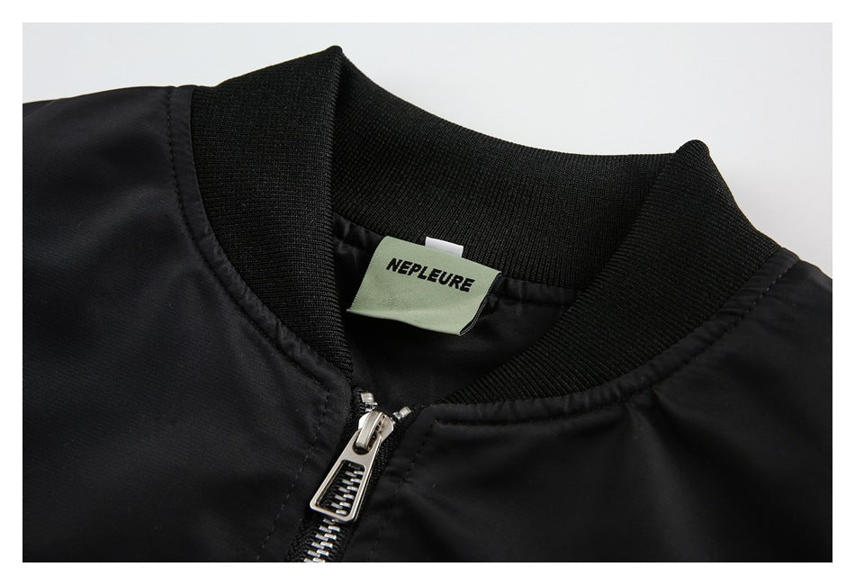 Close-up of the black bomber jacket's ribbed collar, metal zipper, and pale green NEPLEURE neck label.