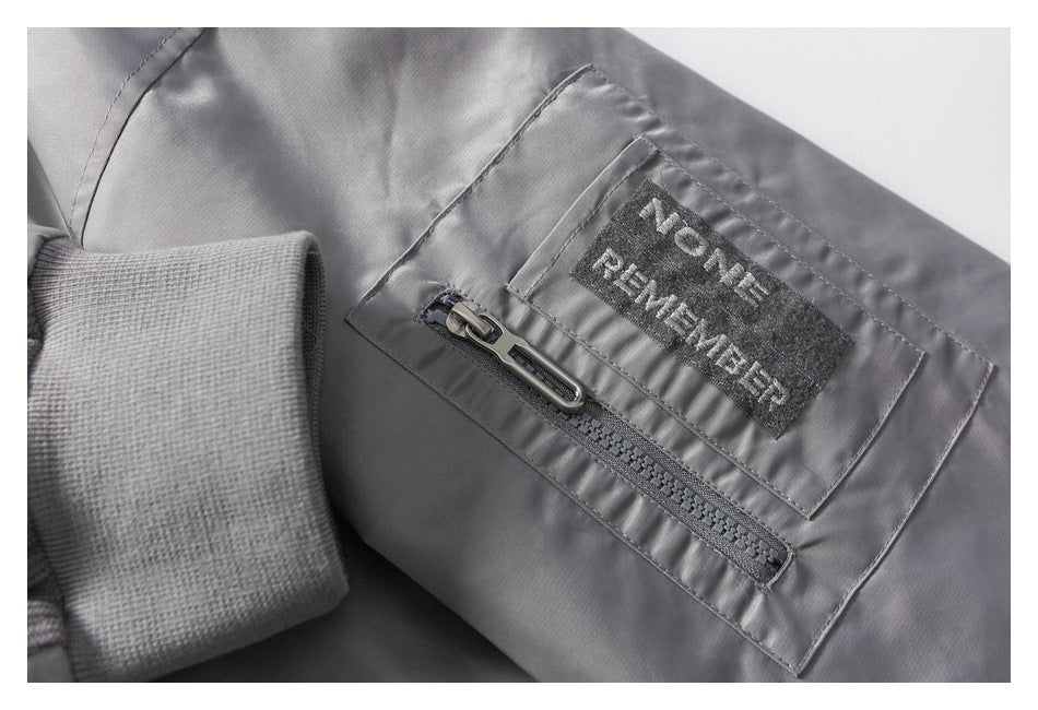 Close-up of a gray zippered pocket, knit cuff, and sewn-on text patch.