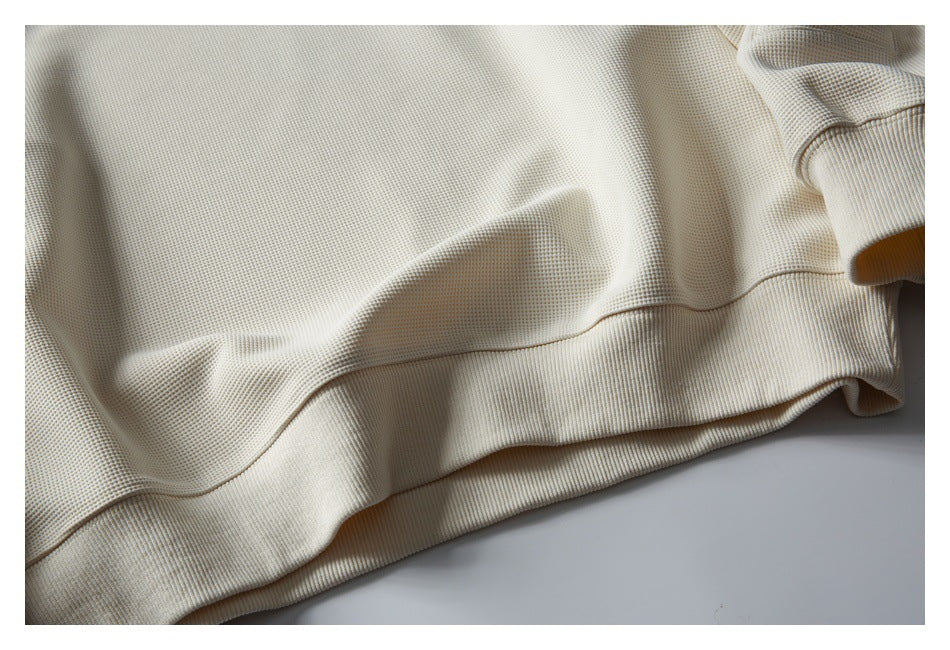 Close-up of the ivory sweatshirt's textured body and wide ribbed bottom hem.