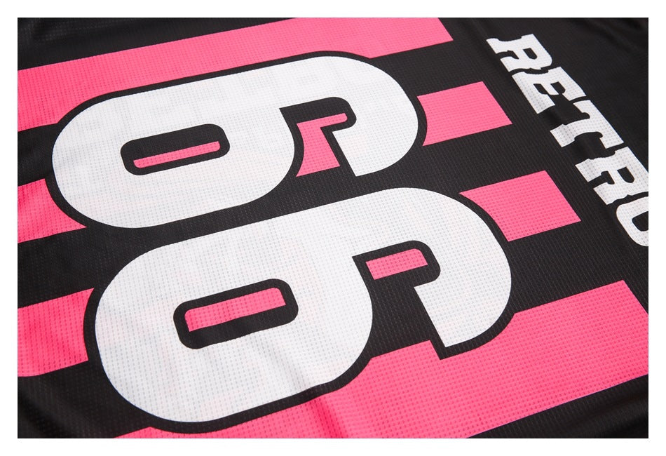 Close-up of a black and bright pink jersey with oversized white numerals and printed lettering.