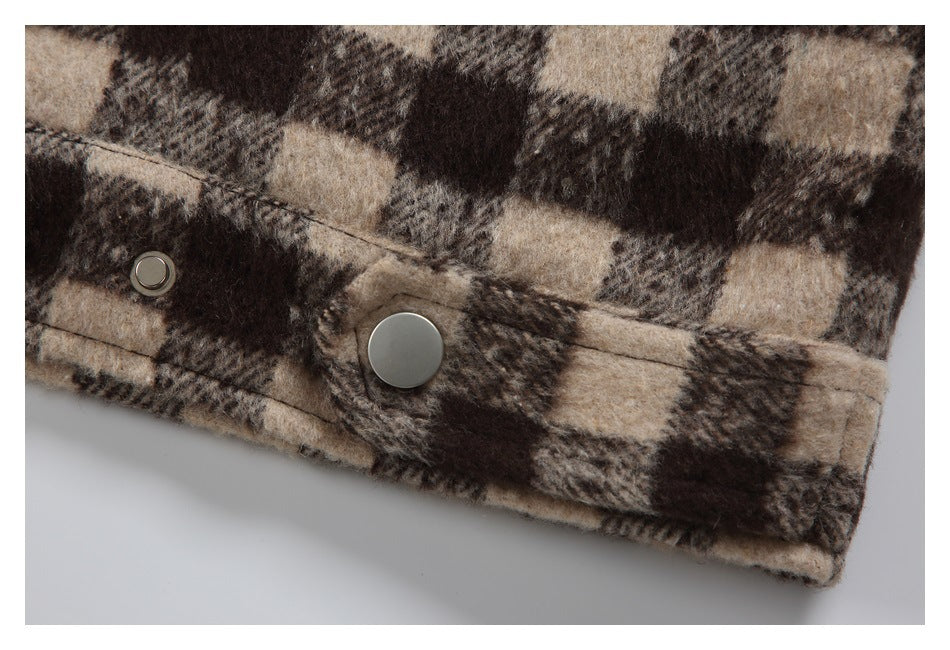 Close-up of two metal snap fasteners on the edge of a brown and beige plaid garment.