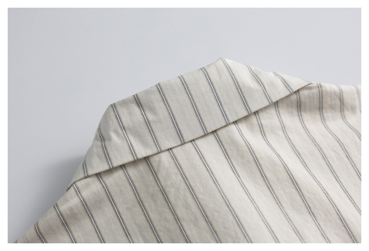 Close-up of the collar and upper body of an ivory shirt with fine dark stripes.