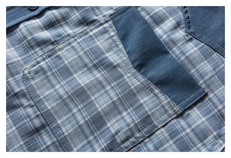 Close-up of a shirt pocket and contrasting denim panel against a gray-blue plaid pattern.